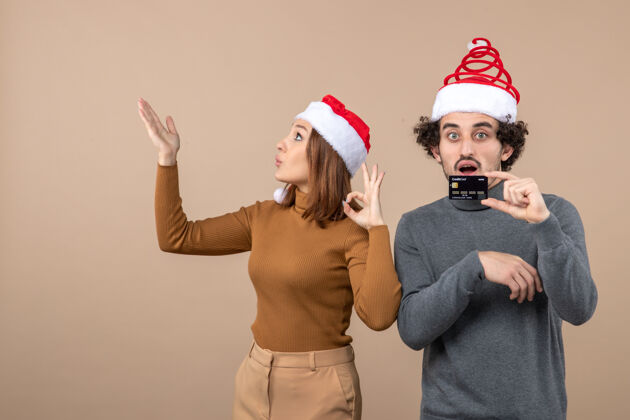 快乐圣诞节心情激动满意惊喜酷酷情侣戴红色圣诞老人帽出示银行卡男性人穿着