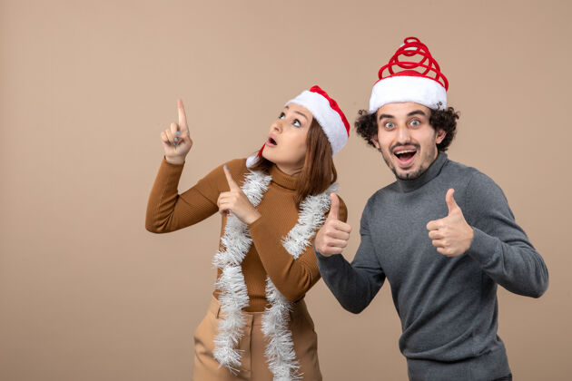 兴奋圣诞节心情激动酷满足可爱情侣戴着红色圣诞老人帽一起玩酷灰色人们
