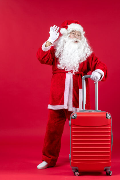 十二月红墙上的圣诞老人和他的红包的正视图包快乐圣诞老人