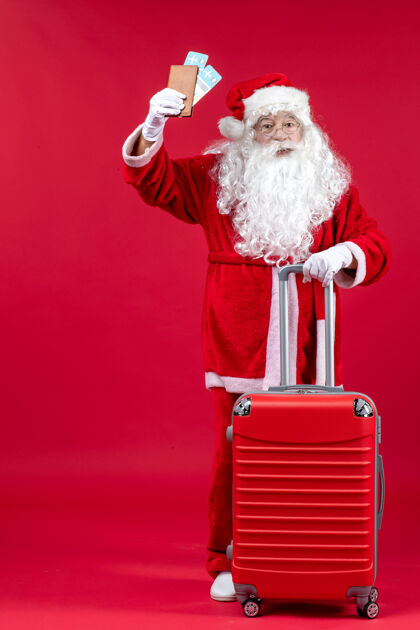 前面圣诞老人的前视图 带着包 拿着票 准备在红墙上旅行人们准备服装