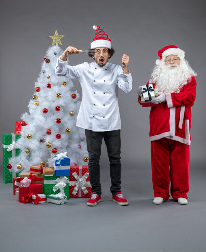 男人圣诞老人和男厨师在灰色墙上围着圣诞礼物的正视图圣诞快乐圣诞老人圣诞