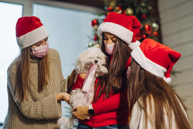 圣诞老人除夕夜 几个女孩在家里和一只小狗玩宠物冠状病毒19保护