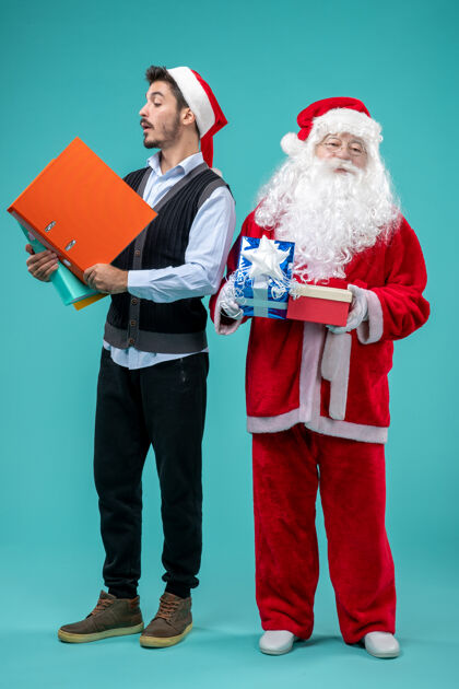 圣诞节前视图圣诞老人与年轻的男性和礼物上的蓝色背景商务圣诞老人年轻