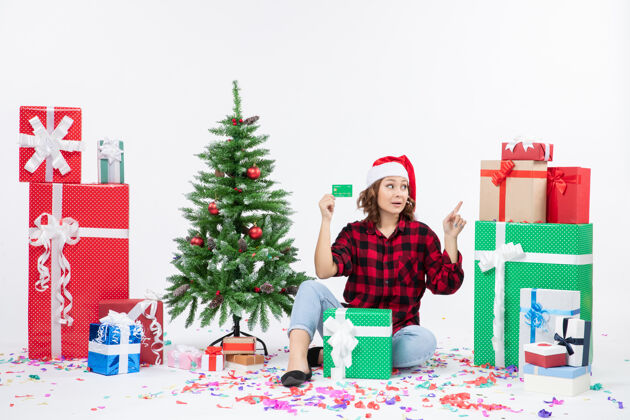 礼物正面图：年轻女子围坐在白墙上 手里拿着绿色的银行卡礼物十二月坐