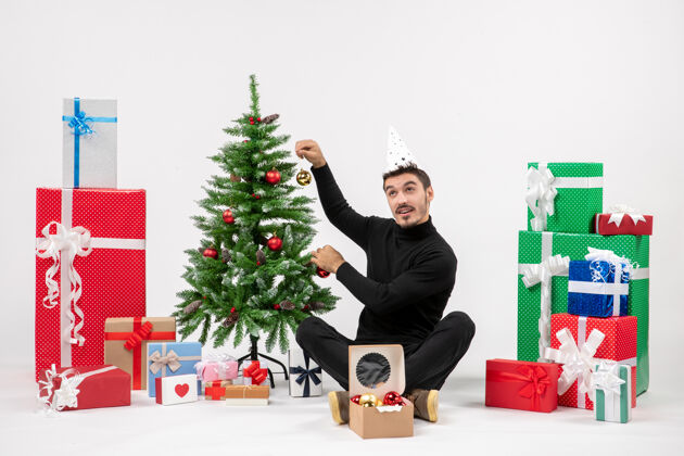 节日正面图：年轻人围坐在白色的墙上 手里拿着圣诞礼物抱着人十二月