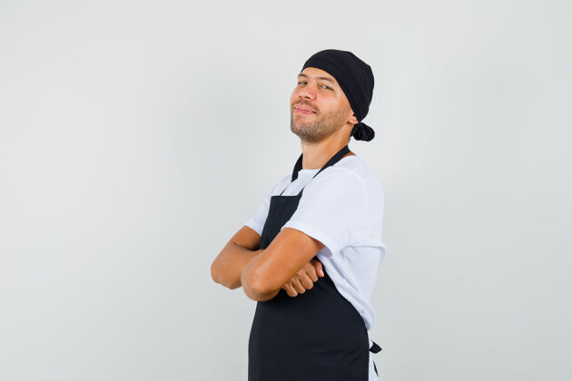 男性面包师身穿t恤 围裙 双臂交叉站着 看上去很高兴肖像自信生意