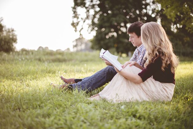男人一对夫妇在阳光下的花园里一起读圣经交流坐着肖像