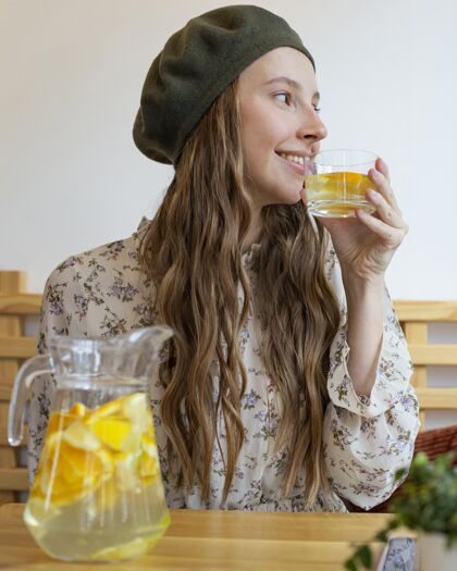食品坐在桌边喝柠檬水的女人的画像饮料健康食品天然
