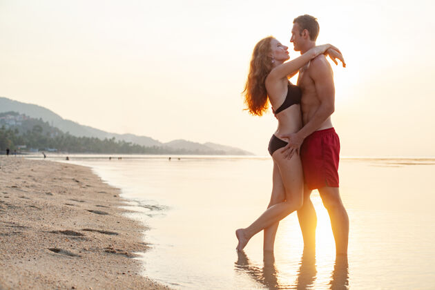 女性年轻性感浪漫的情侣在夏天的沙滩上快乐地穿着泳装玩男朋友微笑肖像