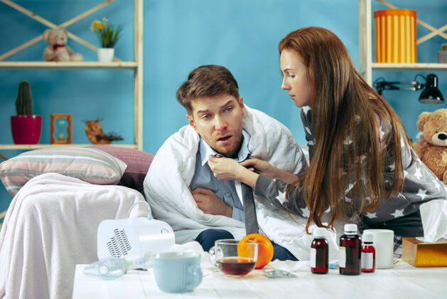 体温计发烧的病人躺在床上发烧他的妻子照顾他疾病 流感 疼痛 家庭观念在家放松保健观念夫妇家庭病