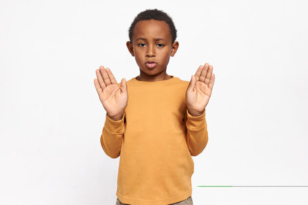 种族穿着运动衫的严肃自信的非洲裔美国小学生的肖像 他伸出双手 手掌张开 做出停止的手势保护手势禁止
