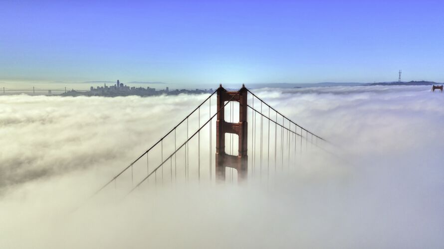 金色美丽的空中拍摄了一座被云层和蓝天包围的桥的顶部山峰环境国家