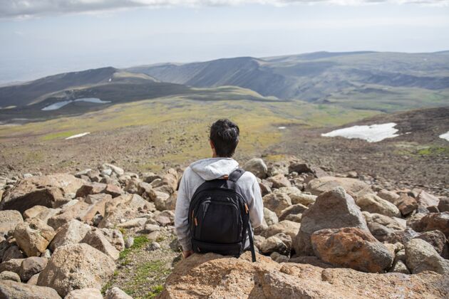 休息选择性聚焦拍摄一个人坐在岩石上美丽的山景岩石天空环境