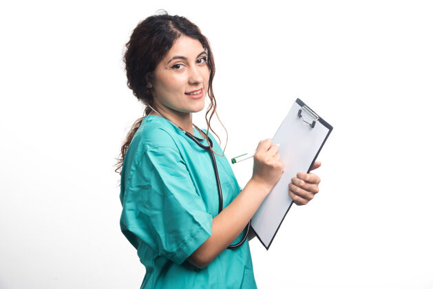 剪贴板带听诊器的女医生在白色背景的剪贴板上写东西高质量的照片听诊器制服人