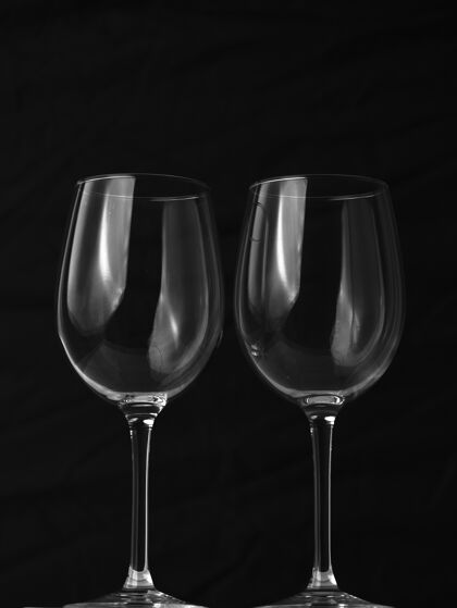 灯光黑色背景上两个空酒杯的垂直镜头聚会透明立式