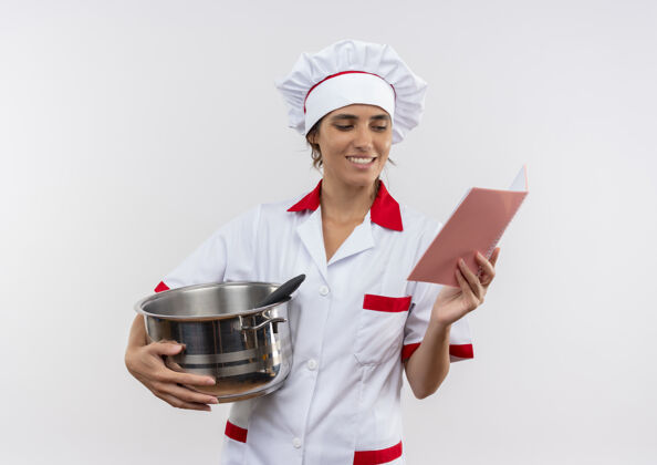 穿着年轻的女厨师面带微笑 穿着厨师制服 拿着平底锅 看着手里的笔记本 还有复印空间厨师笔记本女