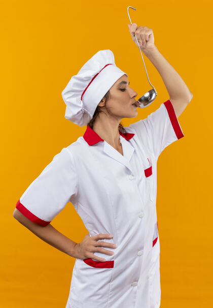 制服站在剖面图年轻的女厨师穿着厨师制服试图从勺子汤勺子试穿