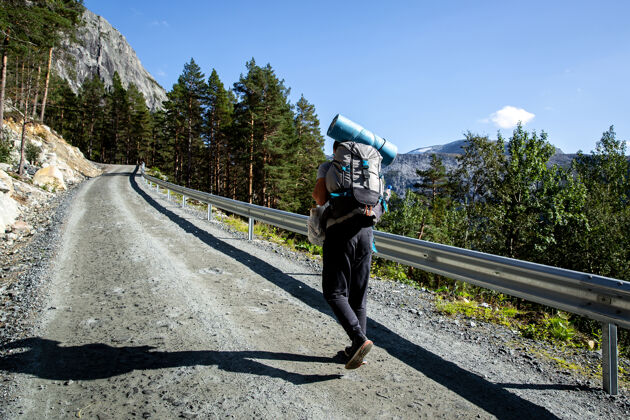 汽车旅馆背着背包的游客正沿着一条碎石路走着山休闲客户