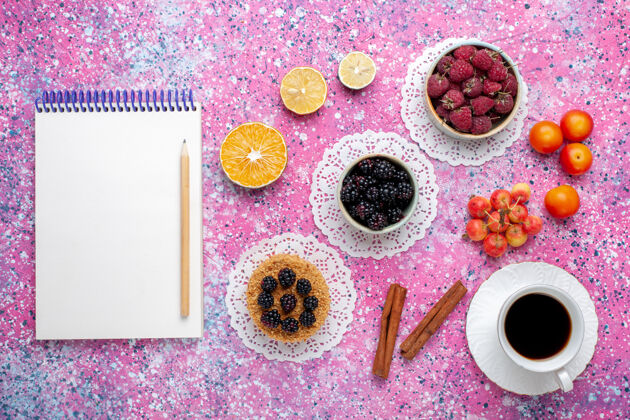 新鲜在粉红色的桌子上可以俯瞰新鲜的野生浆果 覆盆子和黑莓 还有小蛋糕和茶小黄色顶部