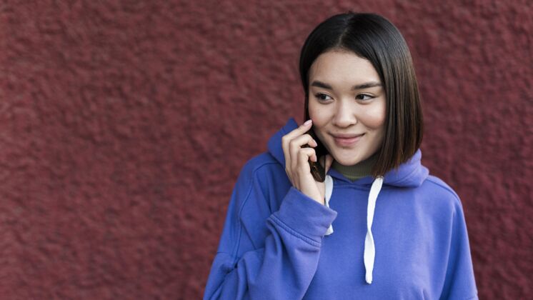 休闲笑眯眯的亚洲女人在电话里用空格键美丽多样性女孩