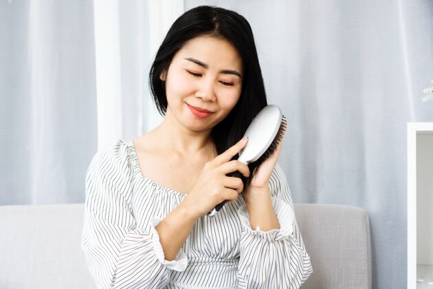 自然亚洲女人用梳子刷洗她美丽的黑发生活方式微笑保健