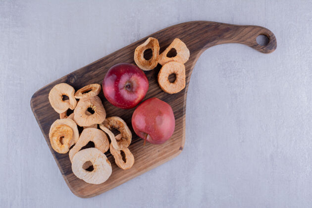 健康多汁的干苹果片和整个苹果放在白色背景的木板上开胃可口晒干