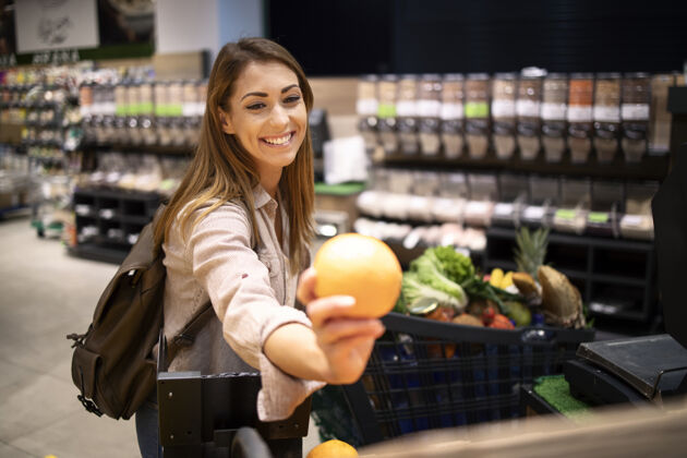 购物狂在水果部的超市里买桔子的美丽微笑的女人超市商店女性