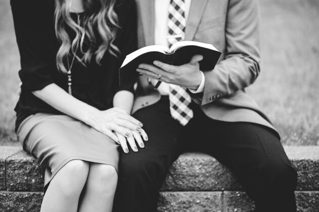花园一对穿着正式衣服的夫妇在花园里一起看书的灰度照片信仰教人