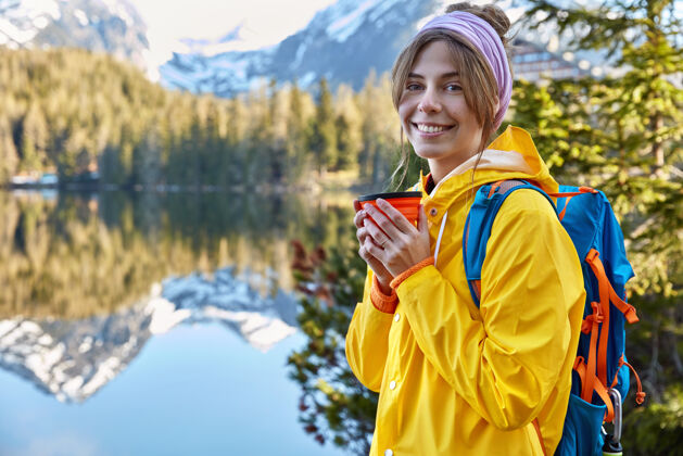 咖啡快乐美丽的女游客在山上度假 用一次性杯子喝咖啡女性湖泊海岸