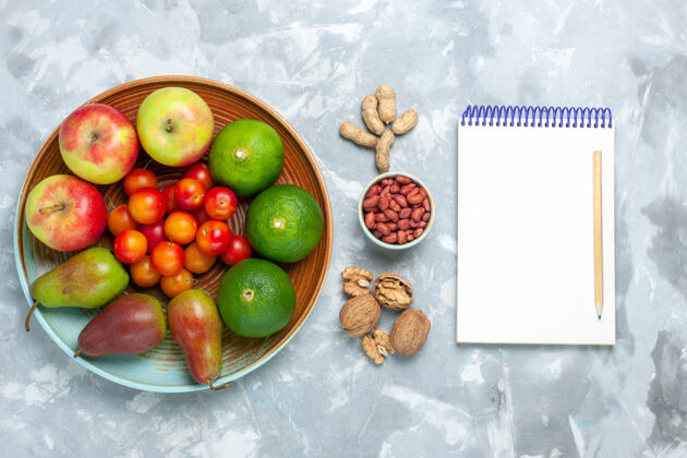 李子俯视图白色书桌上的水果成分苹果梨坚果橘子和李子坚果白健康