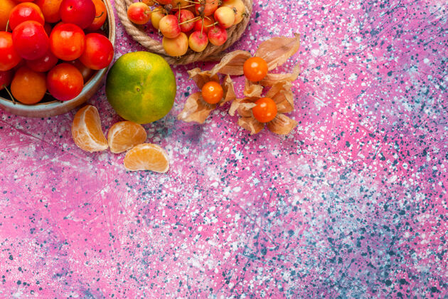 水果顶视图新鲜的酸李子圆润的水果在淡粉色桌子上的小盘子里顶部盘子葡萄
