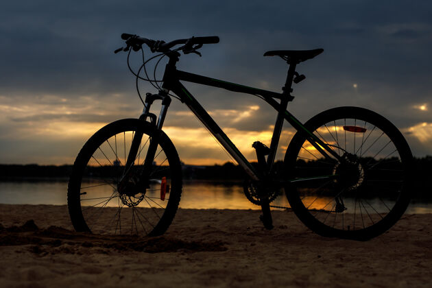 海滩沙滩上运动自行车的剪影日落速度黄昏健身
