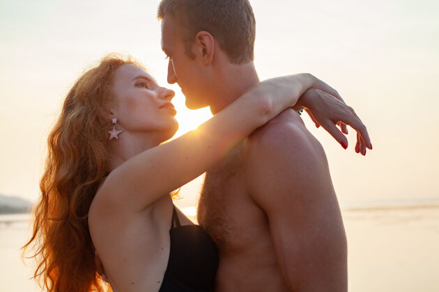 浪漫年轻性感浪漫的情侣在夏天的沙滩上快乐地穿着泳装玩海洋蜜月浪漫