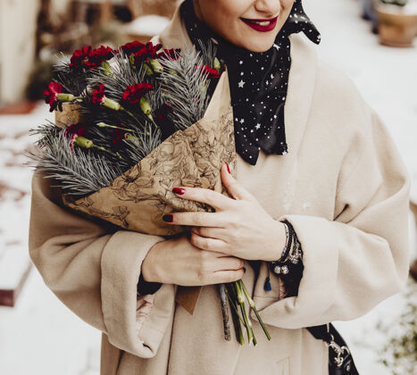漂亮快乐的女人在冬天捧着一束花花束时尚围巾