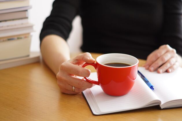 地点一个在家工作或学习的女人手里拿着一杯红咖啡的特写镜头工作学生通讯