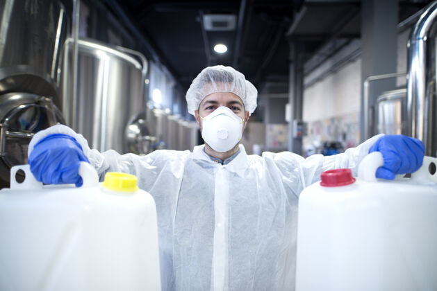 技术戴着防护面具 穿着白色制服 手拿塑料罐的化工工人储罐化学品工业工人