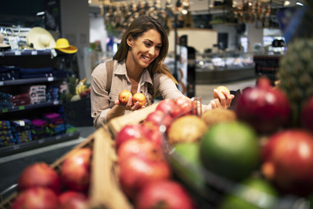 商品在超市里 女人小心翼翼地挑选水果做沙拉商店杂货店购物车