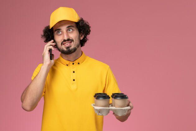 黄色正面图：身穿黄色制服的男信使手拿棕色咖啡杯 粉色墙上挂着电话服务杯子男