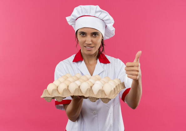 厨师年轻的女厨师穿着厨师制服 手里拿着一批鸡蛋 高兴地站在隔离的粉红色墙上 留着复印空间制服穿年轻