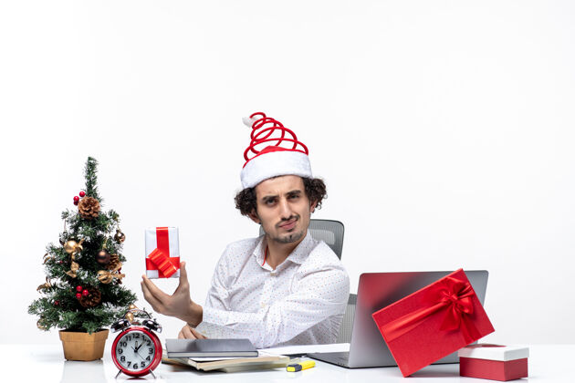 成人圣诞气氛与骄傲的年轻商人圣诞老人帽子和举行他的礼物头脑风暴在白色背景人头脑风暴举行
