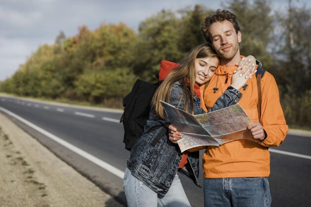 公路旅行一对夫妇拿着地图坐在路边的正视图探险户外旅行