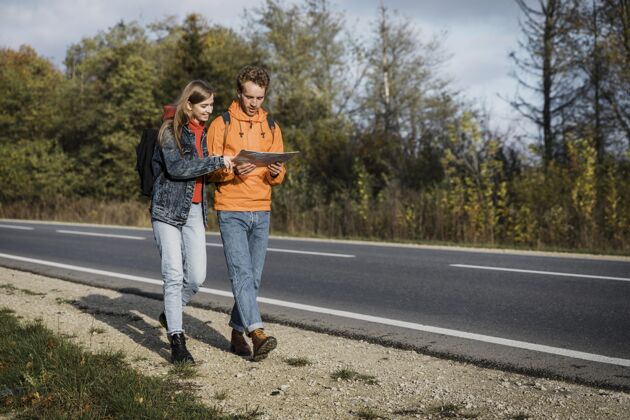复制一对夫妇拿着地图走在路上的正视图旅行探险道路