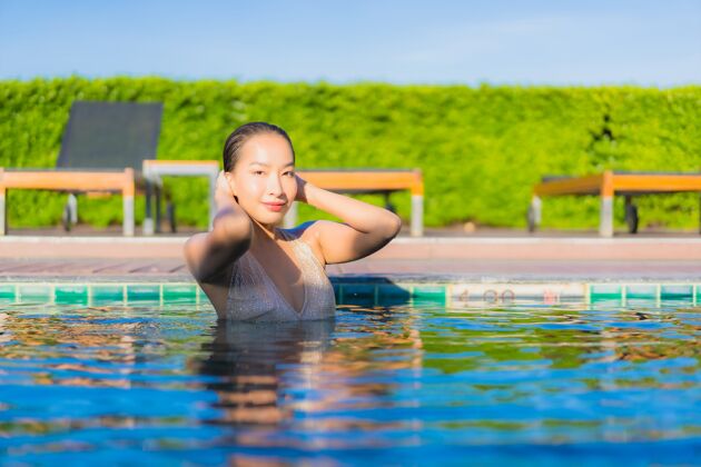 热带美丽的亚洲年轻女子在度假酒店的室外游泳池周围放松的肖像休闲苗条水