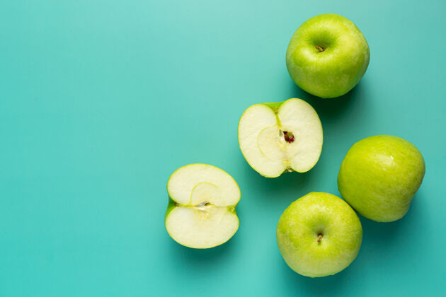 护理新鲜的绿苹果切成两半放在浅绿色的背景上作物保健绿色