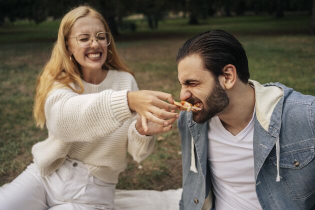 积极给男朋友喂比萨饼的年轻女人可爱假日乐趣