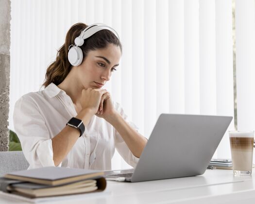 专业人士女商人使用笔记本电脑和耳机的侧视图女商人优雅耳机