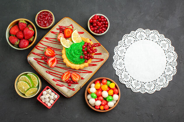 美味顶视图美味的奶油蛋糕和草莓在黑暗的桌子上甜甜的甜点茶草莓餐馆盘子
