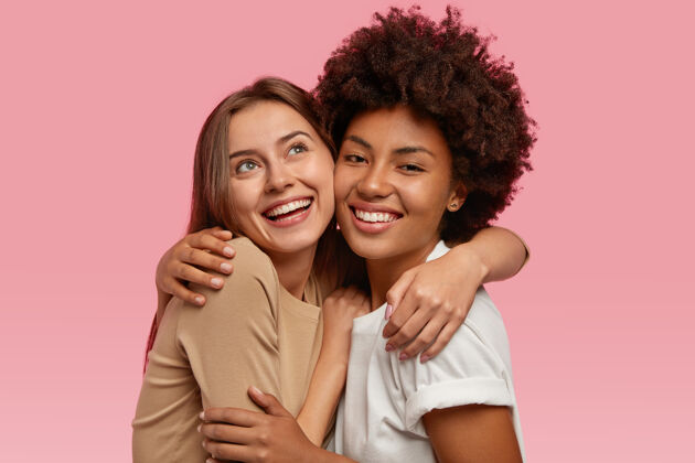 牙齿快乐的两个女人正面拥抱微笑的照片 有梦幻般的表情 展现真情实感满意同伴欣喜若狂