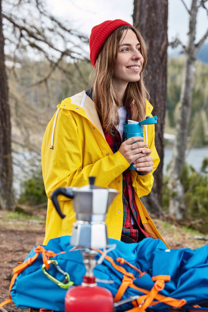 热水瓶人们和露营的概念满意的女旅行者在徒步旅行后喝热水瓶的热饮料背包包炉子