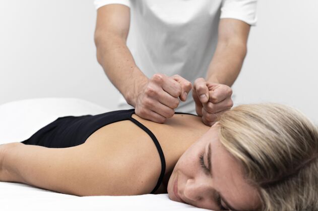 理疗理疗师给女人做背部按摩治疗学运动运动